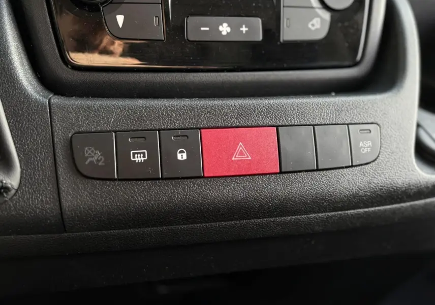 Gros plan sur la rangée de boutons de commande noirs avec bouton rouge d'alerte dans l'habitacle de l'Opel Movano Fourgon 2024.