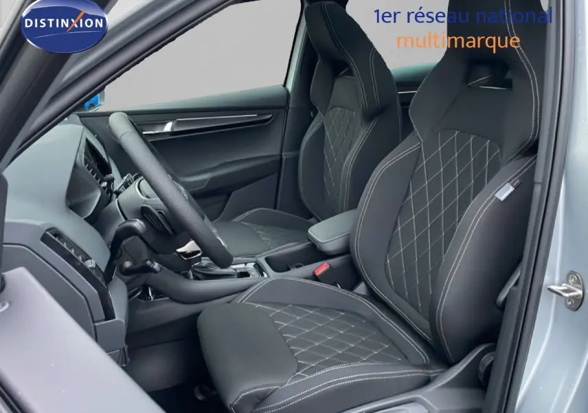 Vue intérieure côté conducteur du Skoda Karoq gris argent 2025, sièges sport noirs avec surpiqûres blanches.