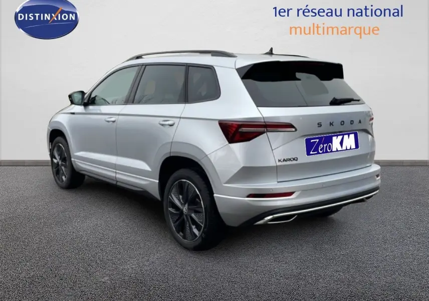 Vue 3/4 arrière droite d’un Skoda Karoq gris argent métal 2025 avec jantes noires et toit noir.