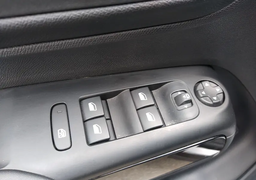 Gros plan sur les commandes de lève-vitres et réglage des rétroviseurs côté conducteur noir du Citroën C5 Aircross 2023.
