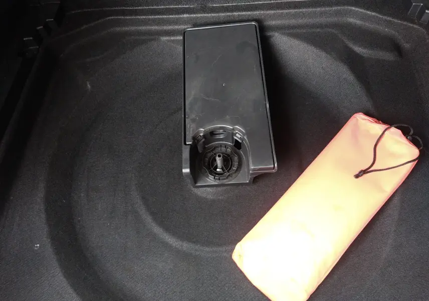 Vue rapprochée du coffre d’un Citroën C5 Aircross 2023 montrant le rangement sous plancher avec un sac orange.