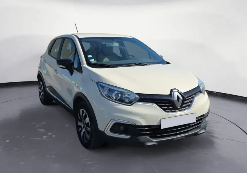 Renault Captur ivoire vue 3/4 avant droit, mettant en valeur ses optiques modernes et sa calandre chromée distinctive.