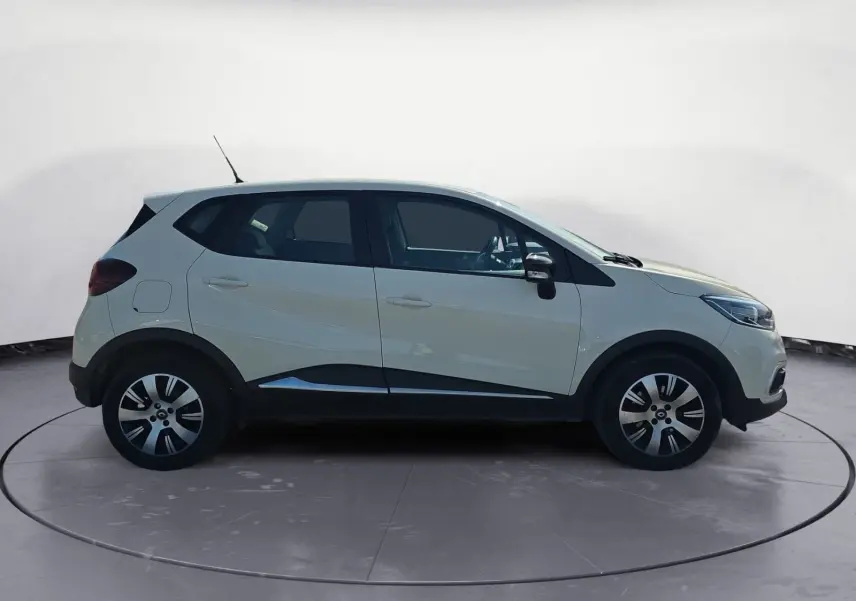 Renault Captur ivoire vue de profil côté gauche, avec jantes alliage et protections noires sur les bas de caisse.