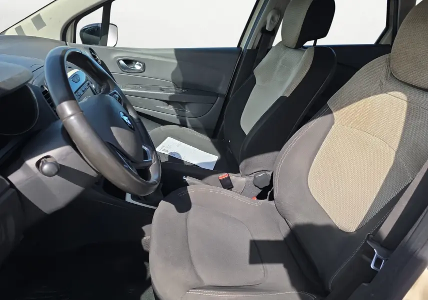 Vue intérieure côté conducteur du Renault Captur ivoire 2018, montrant les sièges bi-ton et le volant cuir.