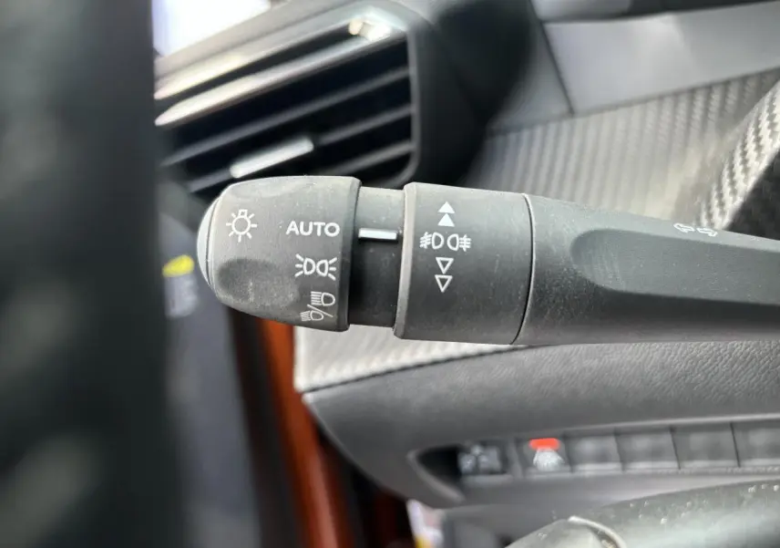 Gros plan sur la commande des phares et clignotants dans l'habitacle d'une Peugeot 2008 Orange Fusion 2021.
