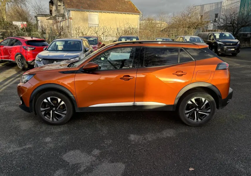 Vue de profil côté gauche d'un Peugeot 2008 2021 orange fusion avec jantes alliage et vitres teintées.