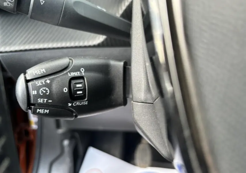 Gros plan sur la commande de régulateur de vitesse à gauche du volant dans un Peugeot 2008 Orange Fusion 2021.