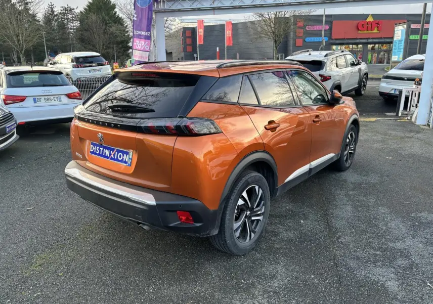 Vue 3/4 arrière droite d'un Peugeot 2008 orange fusion avec toit noir et feux arrière LED distinctifs.