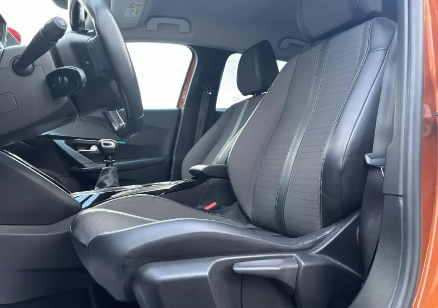 Vue intérieure côté conducteur du Peugeot 2008 2021 Orange Fusion, sièges tissu et cuir avec levier de vitesse manuel visible.