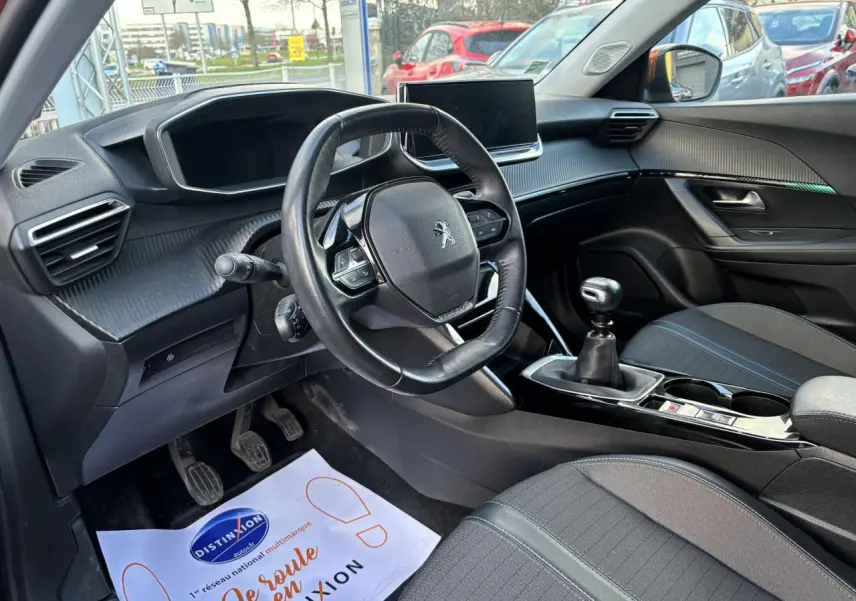Intérieur avant droit du Peugeot 2008 2021 essence Orange Fusion, volant cuir compact et boîte manuelle visible.