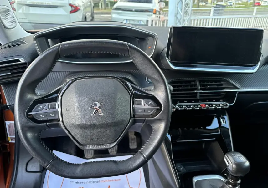 Vue intérieure centrée sur le volant cuir Peugeot et la console avec écran tactile du 2008 Orange Fusion 2021.