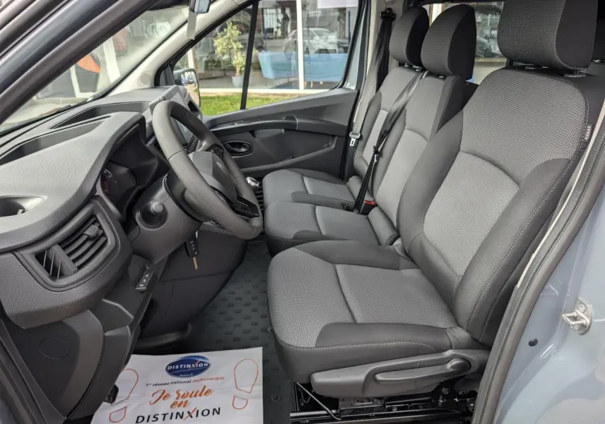 Intérieur côté conducteur du Renault Trafic Fourgon gris 2024, montrant la banquette tissu Kompo Black et le tableau de bord.