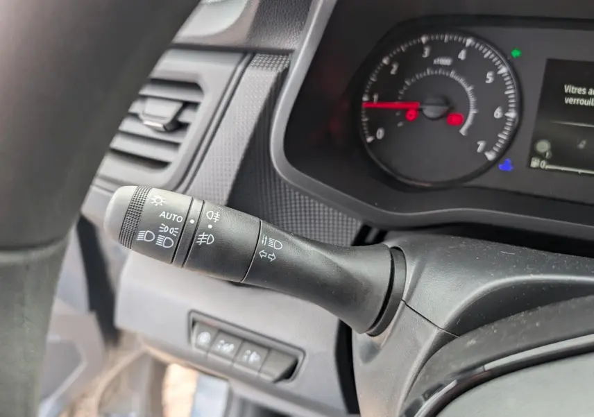 Gros plan sur la commande des phares et clignotants à gauche du tableau de bord du Renault Trafic Fourgon gris 2024.