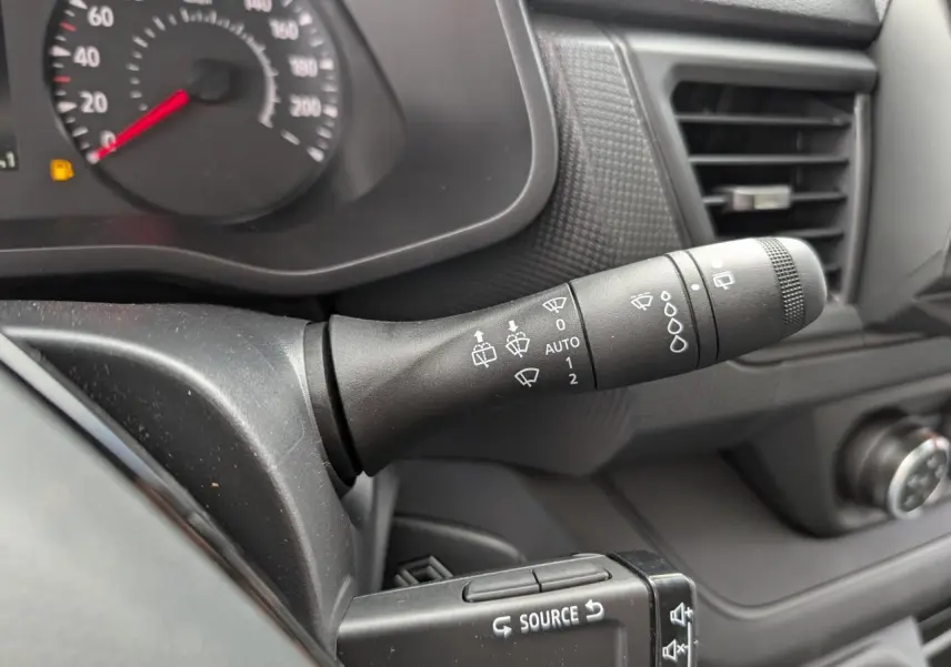 Gros plan sur la commande d’essuie-glace à gauche du tableau de bord noir du Renault Trafic Fourgon gris 2024.