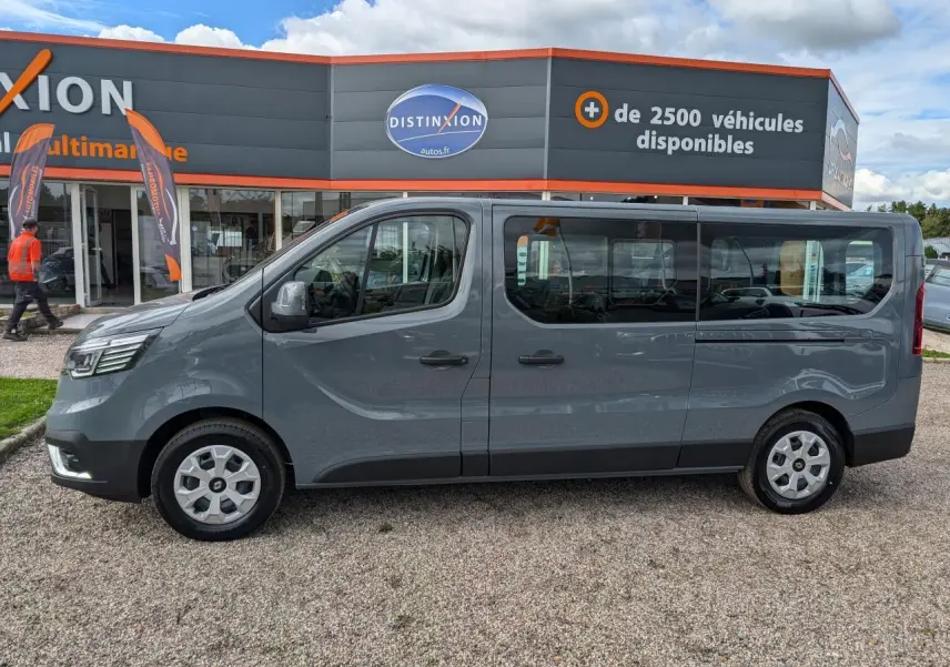 Profil côté gauche du Renault Trafic Fourgon gris 2024 avec vitres latérales et jantes en alliage visibles.