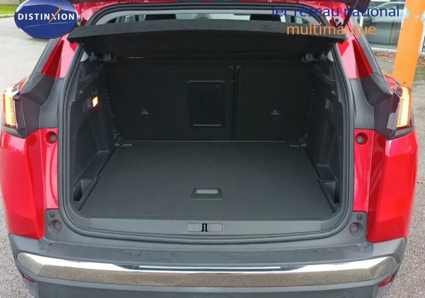 Coffre ouvert vu de l'arrière d'un Peugeot 3008 rouge foncé métallisé, montrant l'espace de chargement vide.