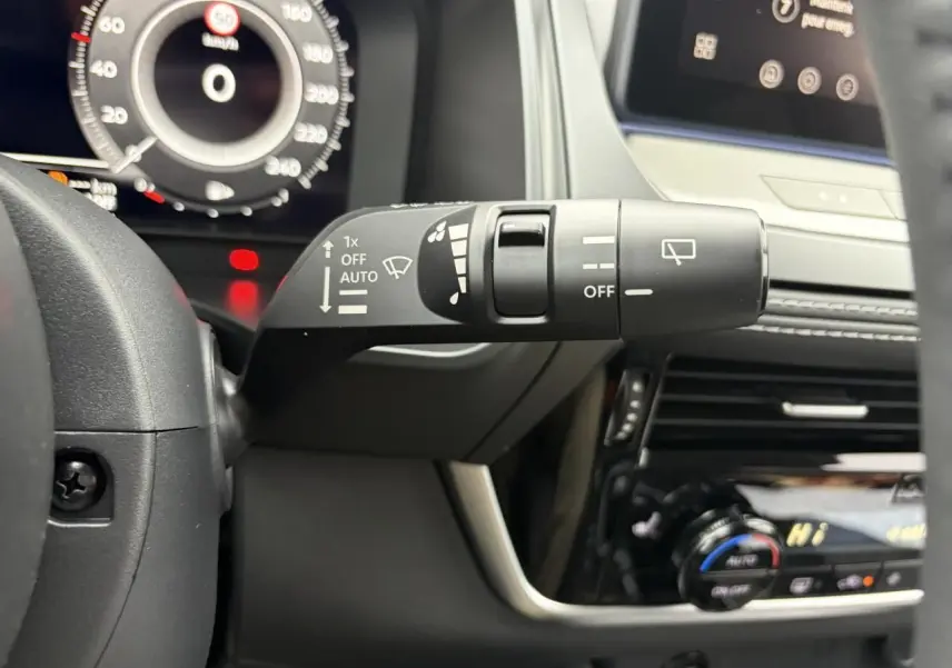 Gros plan sur la commande d’essuie-glace à gauche du volant dans l’habitacle du Nissan Qashqai gris foncé.