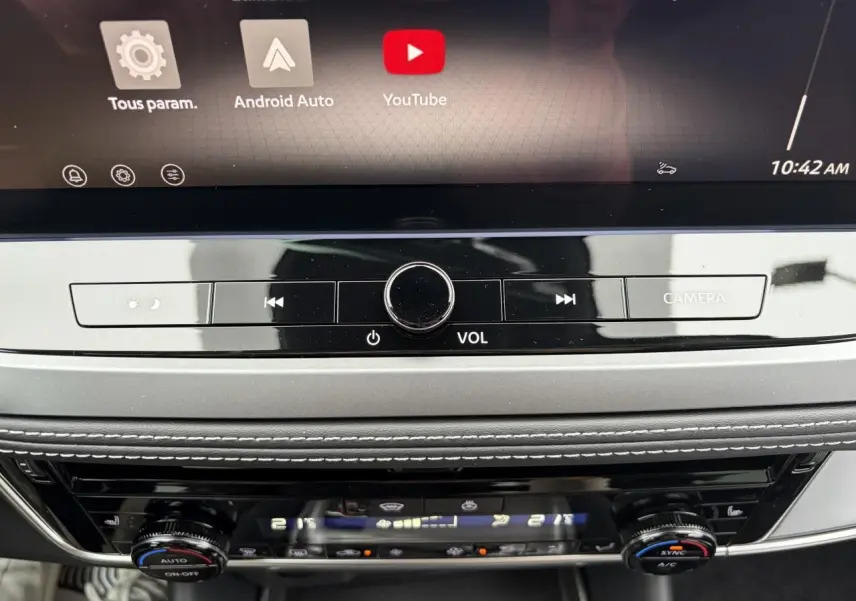 Détail de la console centrale du Nissan Qashqai III 2025, avec commandes volume, climatisation bi-zone et écran tactile.