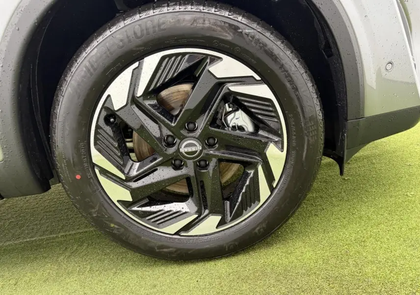 Gros plan sur la jante alliage 18 pouces bicolore noire et argentée du Nissan Qashqai III gris foncé, avec pneu Bridgestone.