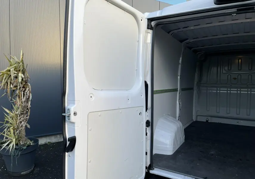 Vue arrière droite du fourgon blanc Opel Movano 2024 avec porte latérale ouverte montrant l'intérieur vide et plancher bois.