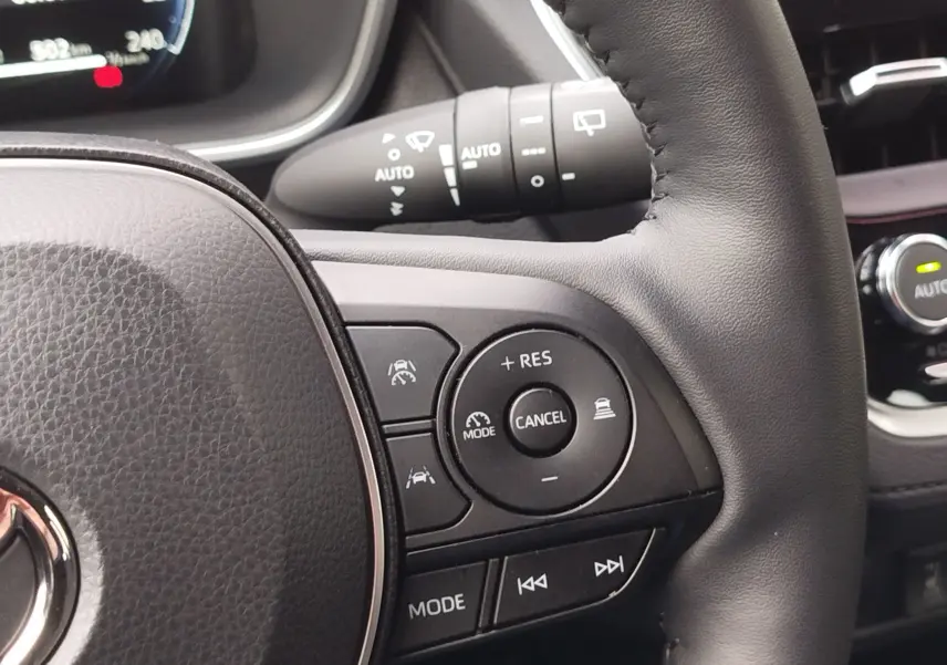 Gros plan sur le volant noir du Toyota Corolla Cross 2025, montrant les commandes de régulateur de vitesse et multimédia.