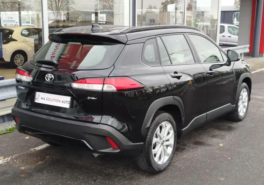 Toyota Corolla Cross 1.8 140ch Dynamic noir intense vue 3/4 arrière droit, avec feux arrière LED et jantes alliage.