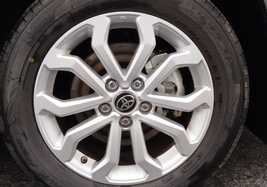 Gros plan sur la jante alliage argentée du Toyota Corolla Cross 2025 noir intense, mettant en valeur le logo Toyota central.