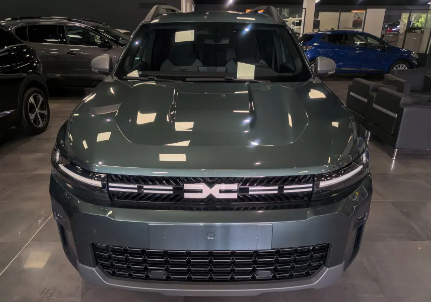 Vue avant d'un Dacia Bigster 2026 vert cèdre en showroom, avec calandre distinctive et phares LED fins.