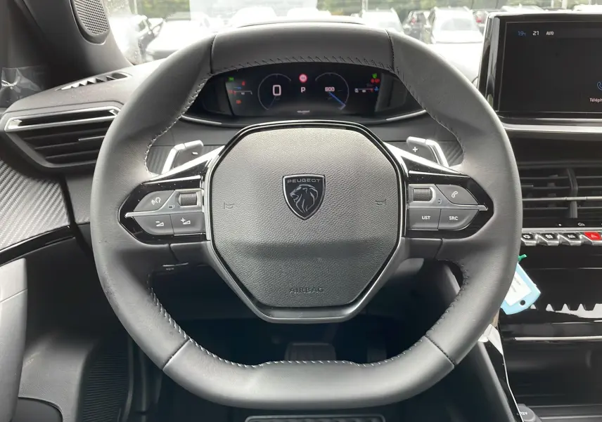 Vue rapprochée du volant cuir noir avec logo Peugeot, tableau de bord numérique et écran tactile du Peugeot 2008 2024.