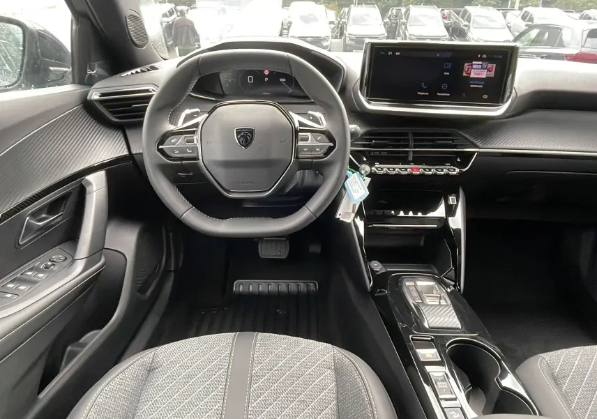 Intérieur du Peugeot 2008 2024 en gris artense, vue frontale du poste de conduite avec volant compact et écran tactile central.