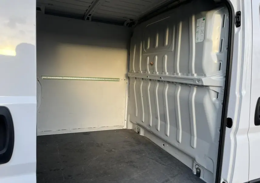 Vue intérieure du fourgon Opel Movano blanc, montrant l'espace de chargement vide avec parois et plancher métalliques.