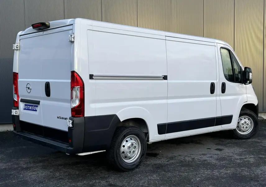 Vue 3/4 arrière droite d’un Opel Movano Fourgon blanc avec porte latérale coulissante et protections noires.