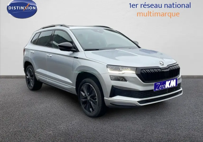 SUV Skoda Karoq gris argent métal en 3/4 avant droit, avec jantes bi-ton noires et toit noir contrasté.