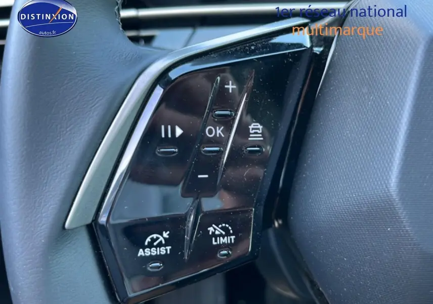 Gros plan sur les commandes au volant noir du Peugeot 5008 Hybrid 145 allure e-dcs6, avec boutons multifonctions visibles.