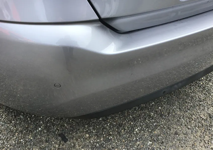 Gros plan sur le pare-chocs arrière gris Artense d'une Peugeot 308 1.5 BlueHDi avec capteurs de recul visibles.