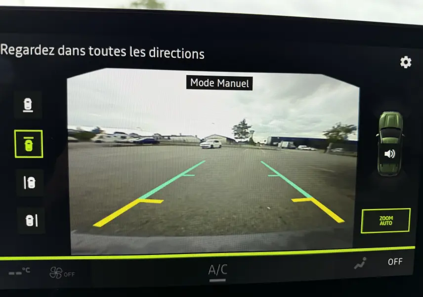 Vue écran caméra 360 du Dacia Duster gris schiste en mode manuel, affichant les lignes d'aide au stationnement arrière.