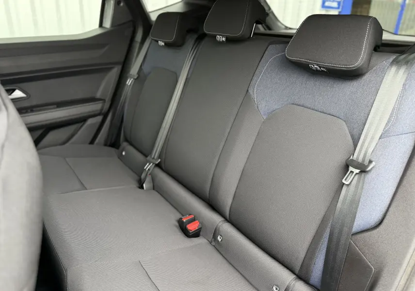Vue intérieure sur la banquette arrière du Dacia Duster 2025, tissu noir et gris avec appuie-têtes et ceintures visibles.