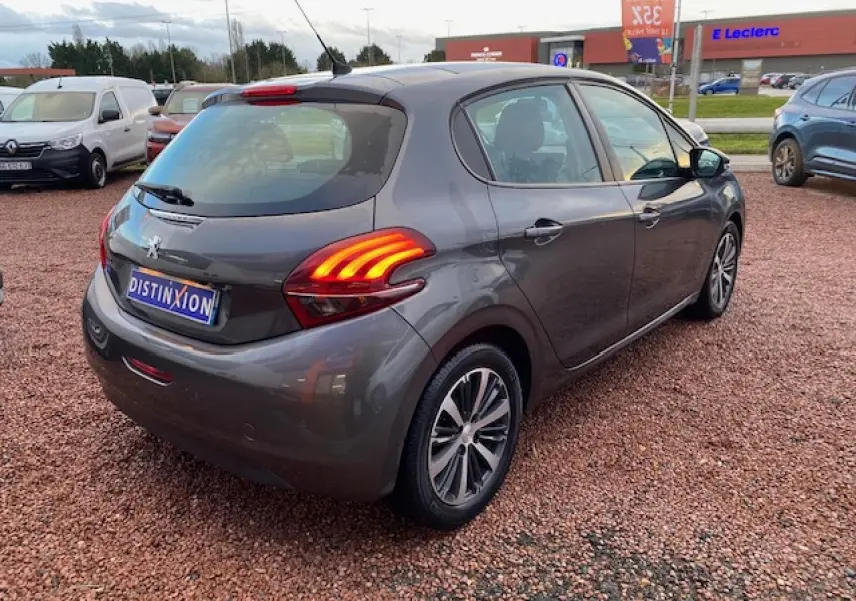 Peugeot 208 gris métallisé vue 3/4 arrière droit, feux arrière griffes 3D allumés et jantes alliage 16 pouces.