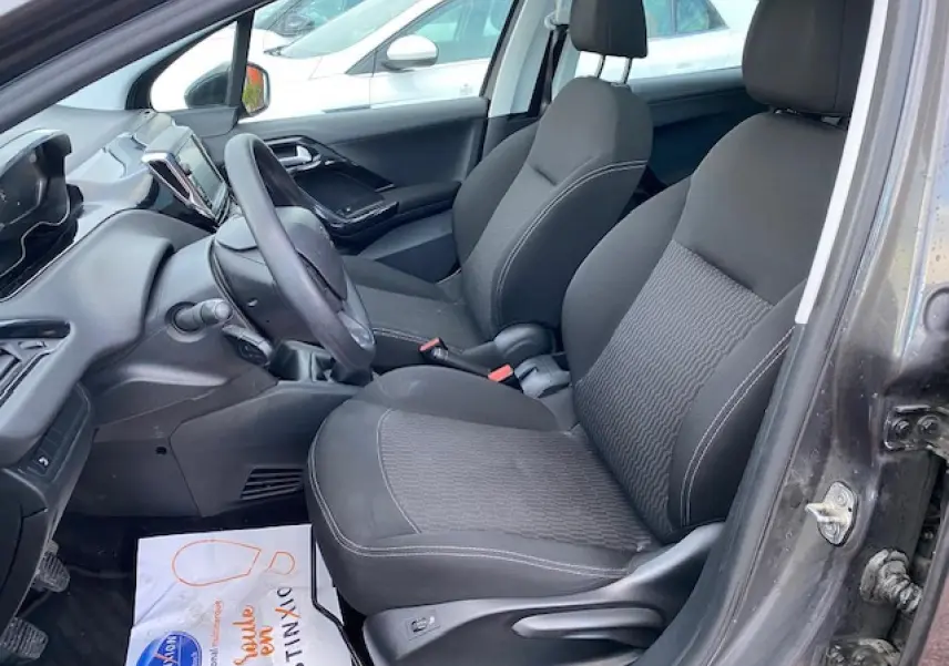 Intérieur côté conducteur d'une Peugeot 208 gris 2017, sièges noirs et tableau de bord avec écran tactile visible.