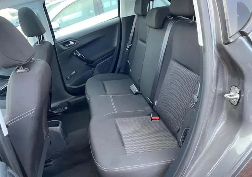 Vue côté droit de l'habitacle arrière d'une Peugeot 208 gris métallisé avec sièges tissu noir et ceinture de sécurité.