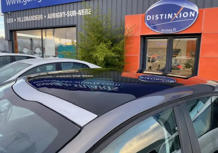 Toit panoramique en verre noir sur Peugeot 208 gris vue côté droit en extérieur devant un garage.