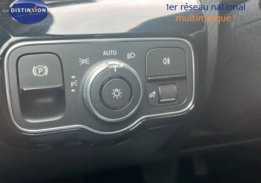 Gros plan sur les commandes d'éclairage et de frein de stationnement de la Mercedes Classe A 180 Business Line noire.