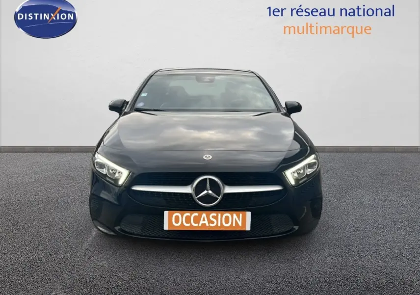 Vue frontale d'une Mercedes Classe A 180 Business Line noire Cosmos Metal avec phares LED allumés sur fond neutre.