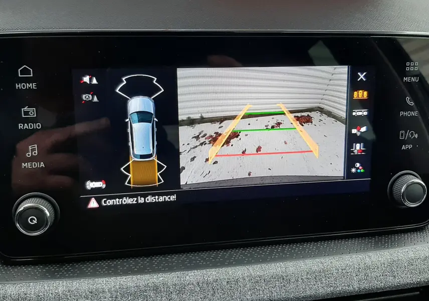 Écran central montrant la caméra de recul et l'alerte de distance du Skoda Kamiq gris graphite, vue intérieure du tableau de bord.