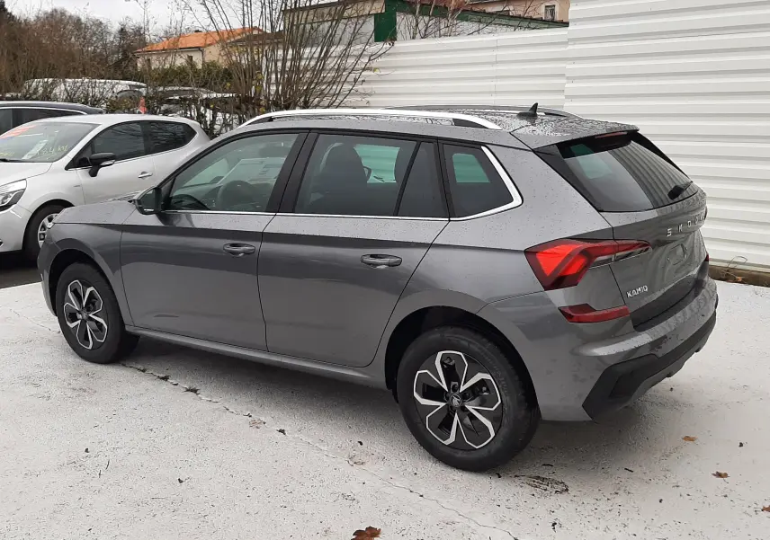 Vue 3/4 arrière côté gauche d'un Skoda Kamiq gris graphite métallisé avec jantes noires et toit ouvrant.