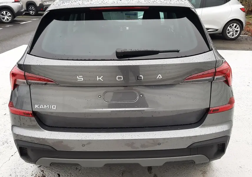 Vue arrière d'un SUV SKODA KAMIQ gris graphite métal 2025 avec feux LED et badge distinctif bien visible.