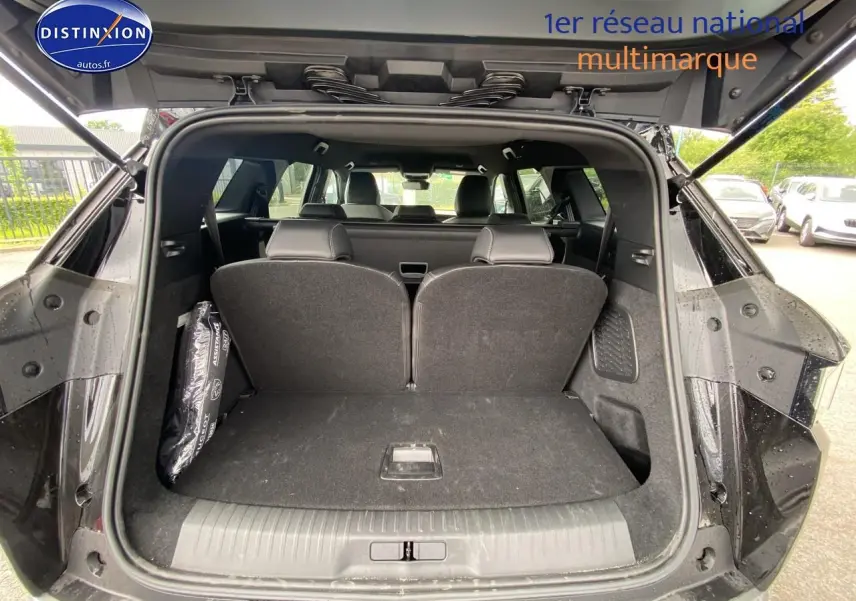 Coffre ouvert vu de l'arrière d'un Peugeot 5008 noir avec sièges arrière en position relevée, intérieur spacieux visible.