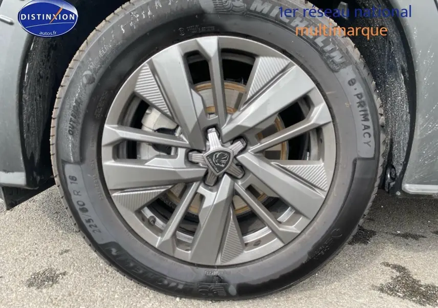 Gros plan sur la jante alu grise et le pneu Michelin d'une Peugeot 5008 noir, côté avant droit.