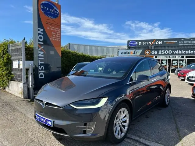 Vue 3/4 avant d'une Tesla Model X gris métallisé 2019 garée devant un concessionnaire Distinxion.