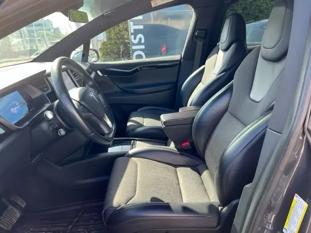 Vue intérieure côté conducteur du Tesla Model X gris 2019, mettant en valeur les sièges en cuir et l'écran tactile central.